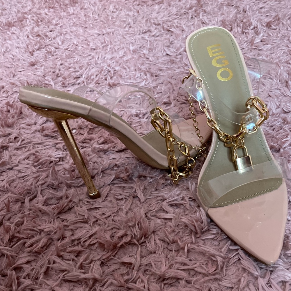 clear ego shoes with a gold heel and a lock decoration around the ankle.